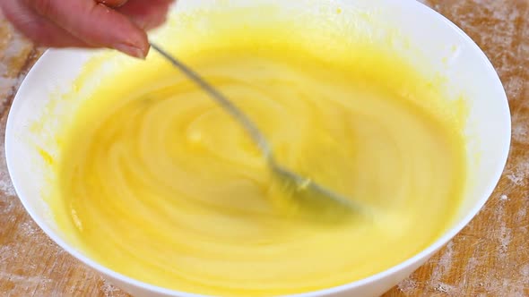 Woman Slowly Moves with an Iron Spoon Liquid Yellow Tests in a Deep Large White Bowl on a Wooden