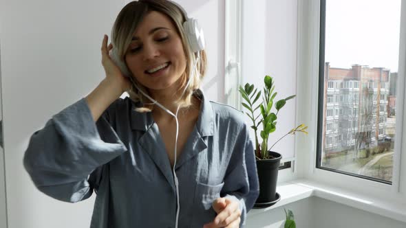 Portrait of cheerful european woman in headphones listening to music