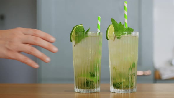 Hand Taking Glass of Mojito Cocktail From Table