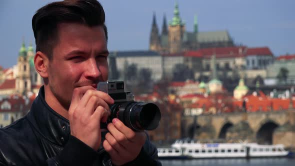 A Young Handsome Man Takes Photos with a Camera - Face Closeup - Town in the Blurry Background