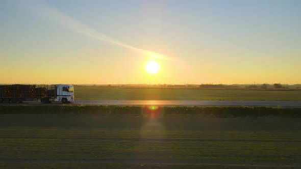 Aerial View of Semitruck with Cargo Trailer Driving on Highway Hauling Goods in Evening