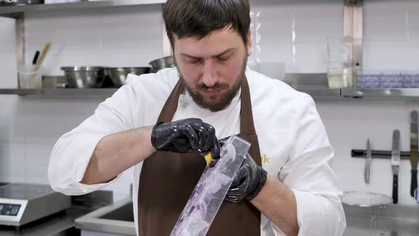 Male Pastry Chef Who Uses a Washcloth to Apply Shiny Candurin to a Mold for Chocolate Spheres