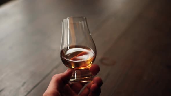 Hand holding and analyzing a whisky glass