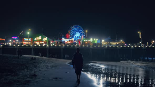 Girl Walking Along Beach to Amusement Night Park