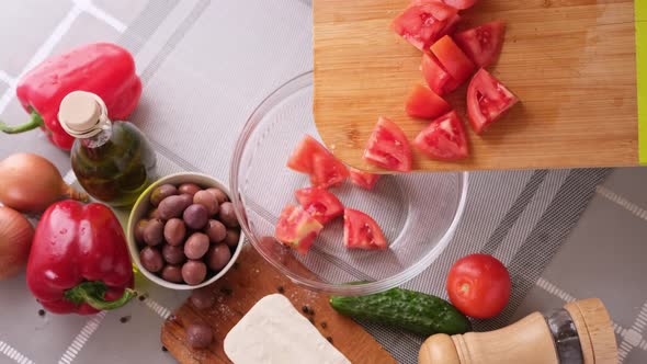 Greek Salad Preparation Series Concept  Woman Pouring Sliced Tomatoes Into a Bowl