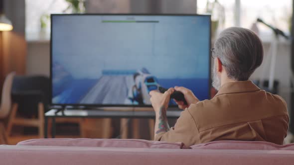 Man Playing Shooter Video Game on TV at Home