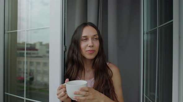 Portrait of a Brunette Who Goes Out on the Balcony with a Mug of Morning Coffee