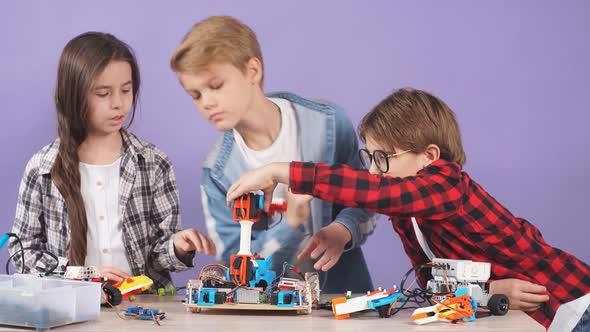 Portrait of Smart Children Aiming To Make a Robot Isolated in Studio.