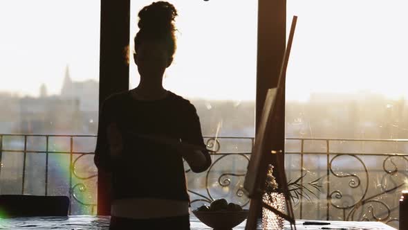 Unrecognizable Figure of Female Artist Drawing on Easel in an Art Studio with Panoramic Windows