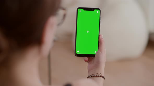 Extreme Closeup of Young Woman Holding Vertical Smartphone with Green Screen Watching Online Video