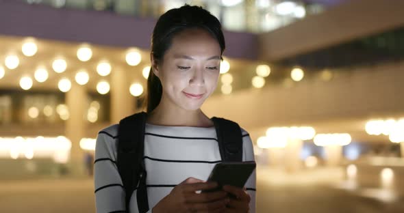 Woman looking at mobile phone in city at night