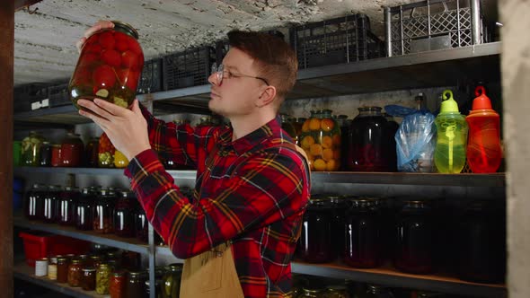 A Young Farmer in Glasses Checks the Quality of Organic Products in a Warehouse in the Basement