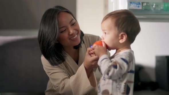 Asian mom feeding the baby a tomato