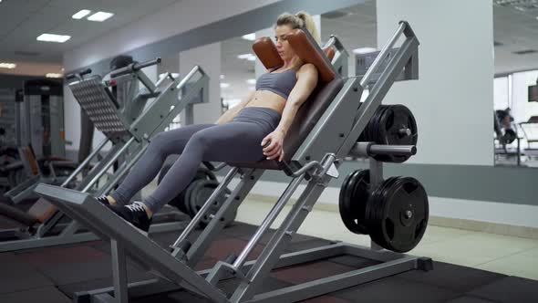 Fit woman practicing back squats in exercise machine