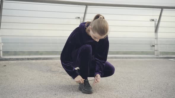 Wide Shot of Young Caucasian Sportswoman Tying Shoelaces and Leaving