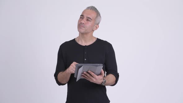 Happy Handsome Persian Man Thinking While Using Digital Tablet