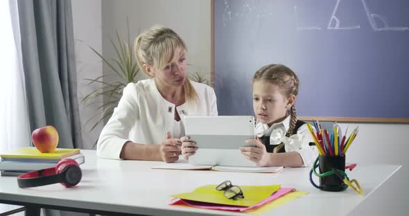 Portrait of Cute Caucasian Schoolgirl Talking To Middle Aged Teacher and Giving Her High Five