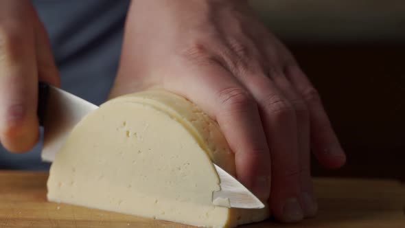 Man Hands Cutting Piece of Cheese on Kitchen Board Close Up