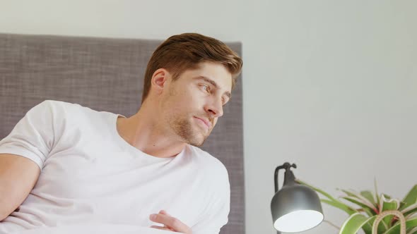 Young man sitting on bed looking outside in the bedroom 4K 4k