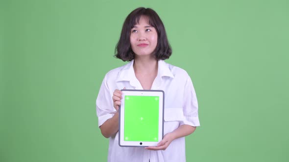 Happy Beautiful Asian Businesswoman Thinking While Showing Digital Tablet