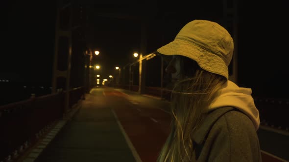 A Girl Stands on the Bridge at Night and Looks at the Lights of the Big City