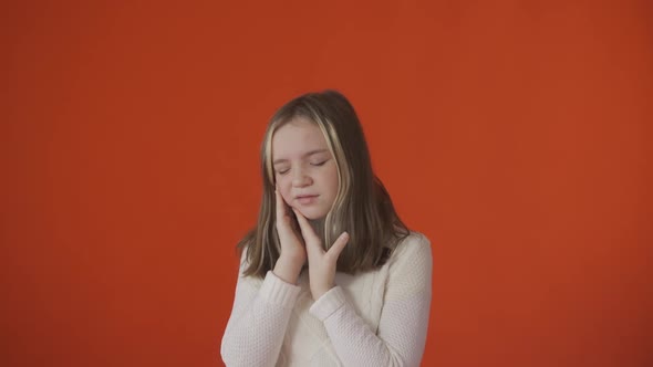 A Little Girl Hurts Her Tooth Against a Orange Background