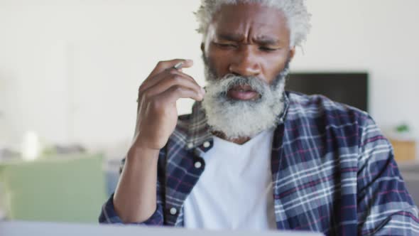 Stressed senior man using laptop at home