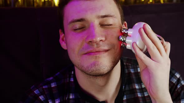 Young Happy Man Using 3d Massager for Face