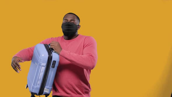 Tourism Pandemic and Health Care Concept Black Man in Medical Mask Picks Up a Travel Suitcase and