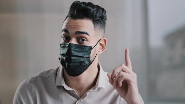 Hispanic Arabic Male Worker Businessman Guy Millennial Man in Medical Mask Raise Index Finger