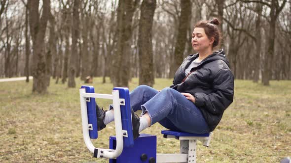 a Woman is Engaged in Mechanical Sports Simulators in the Park on a Walk