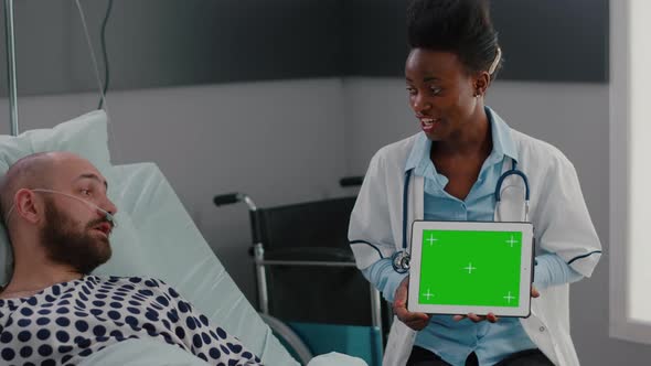 Doctor with Dark Skin Explaining to Woman Patient Resting in Bed About Sickness Treatment