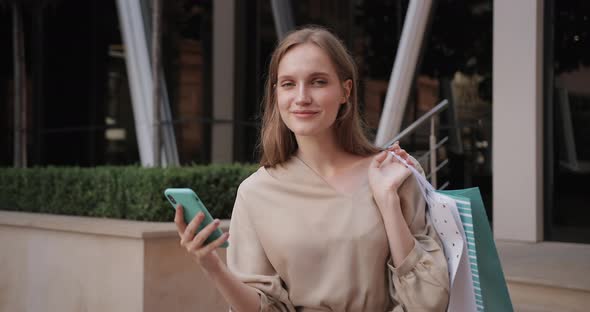 Attractive Woman Raising Head and Looking To Camera While Browsing Internet on Smartphone, Portrait