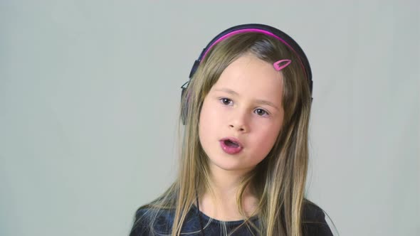 Pretty Smiling Cild Girl Listening to Music in Big Pink Earphones