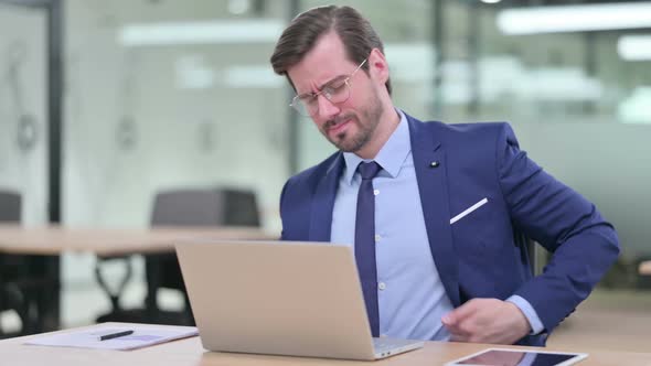 Hardworking Young Businessman with Laptop Having Back Pain