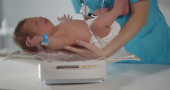 Cropped Shot of Nurse Weighting on Scales Newborn Baby