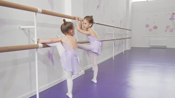 Two Cute Little Ballerinas Stretching at Ballet School Together