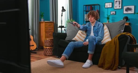 Teen Boy Sitting on Cozy Couch and Watching Comedy on TV Laughing with Humorous Jokes