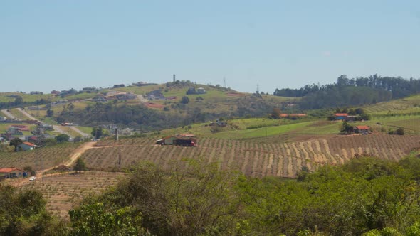 Distant view of simple small farms on the hills of Brazil, divided by dirt roads and paths leading t