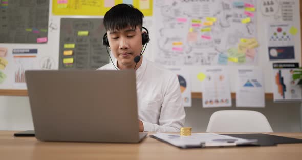 Happy male wears headset video calling on laptop