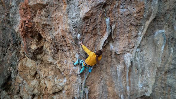 Aerial Slow Motion Back View Strong Man Rock Climber Climbs on Overhanging Limestone Cliff with