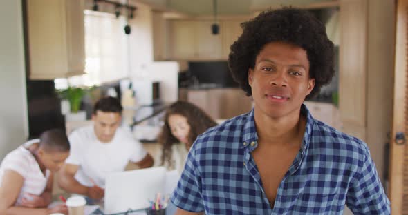 Happy african american man in kitchen with diverse friends working in background