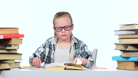 Girl Sits at the Table Leafing Through the Book. White Background