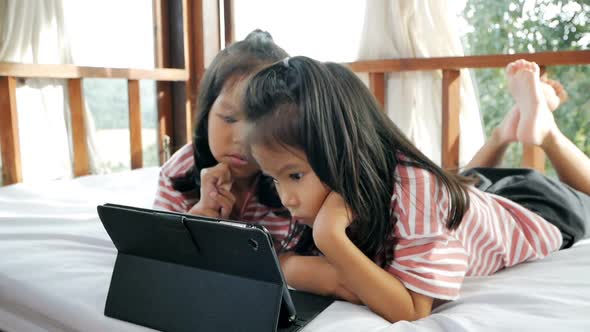 Little girls is looking at tablet on the bed. Slowmotion shot in light nature