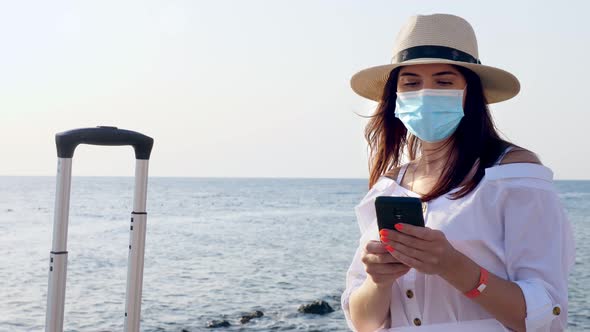 Woman in Protective Mask, Summer Clothes, Sunglasses, Sun Hat and with Travel Suitcase, Luggage