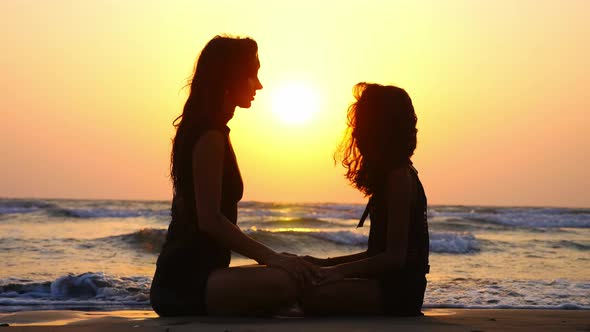 Mom and Daughter Are Meditating Together on the Ocean at Beautiful Sunset.