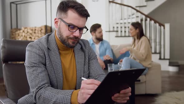 Psychologist which Making Notes on the Background of Smiling Young Married Couple