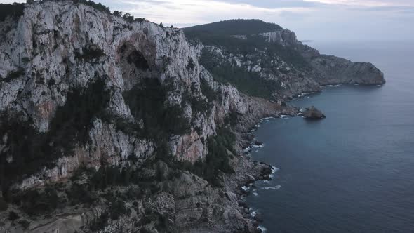 Awe Inspiring rocky cliffs and caves at Ibiza Island, drone pedestal shot