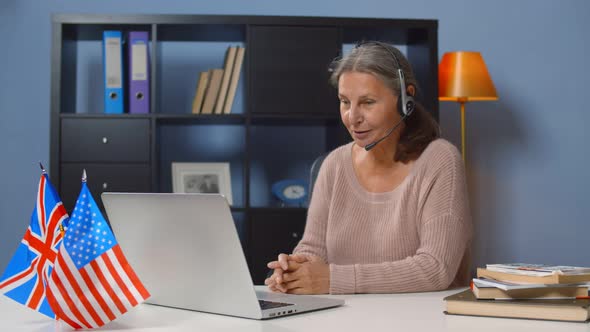 Senior Female English Teacher in Headset Giving Online Lesson on Laptop