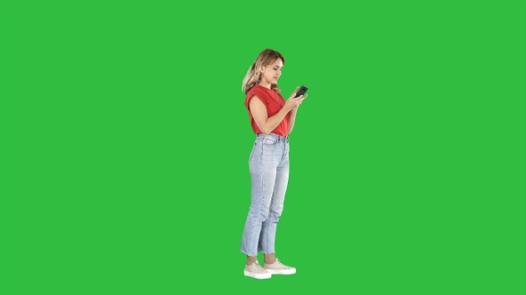 Smiling casual woman holding smartphone using it on a Green